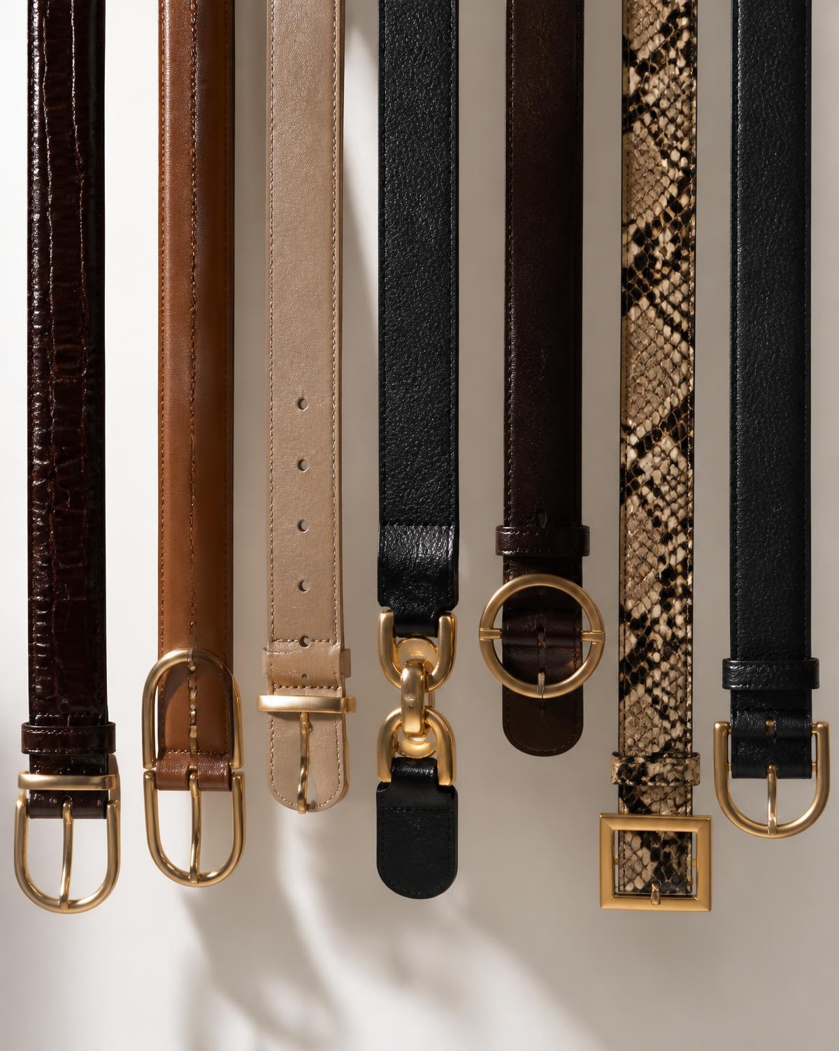 Row of leather fashion belts with metal buckles